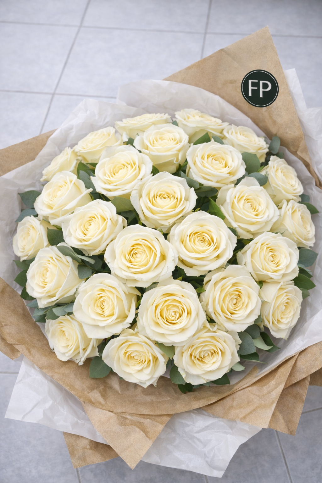 Bouquet of white roses wrapped in brown paper on a light grey floor.