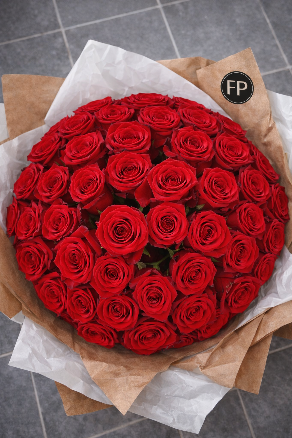 Bouquet of 50 red roses wrapped in brown paper on a grey tiled floor. Ecuadorian roses 