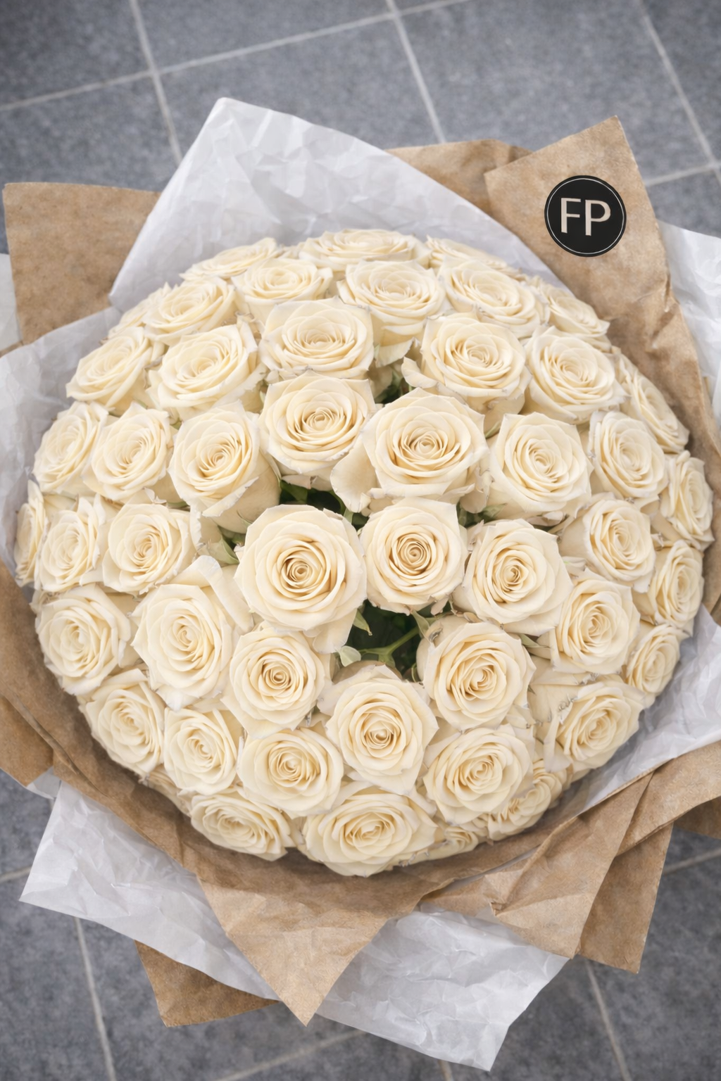 Bouquet of white roses wrapped in brown paper on a grey surface