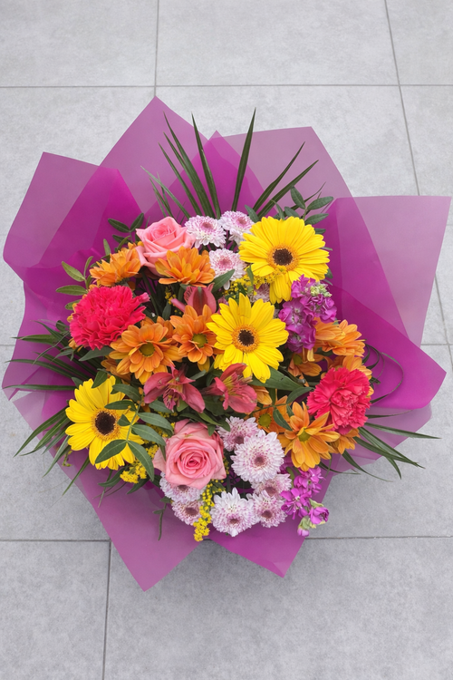 Colorful bouquet of flowers with pink, yellow, and orange colors on a gray tiled floor.